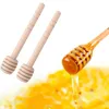Two wooden honey dippers are shown on the left, and a third dipper is shown on the right, covered in honey and dripping into a pool of honey. Podgląd zdjęcia produktu