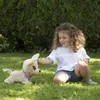 A young girl is playing with a stuffed dog in a grassy garden. Anteprima dell’immagine prodotto