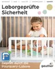A young girl is playing in a crib with a white bed guard. Produktbild-Vorschau