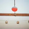 A single red and white spherical light is hanging from a wire, with a wooden beam and other lights in the background. Produktbild-Vorschau