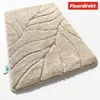 A beige bath mat with a leaf pattern is shown on a white background. Anteprima dell’immagine prodotto