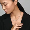 A woman wearing a black jacket and a silver necklace. Podgląd zdjęcia produktu