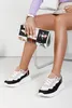 A person is sitting on a chair, holding a clutch bag and showing off their shoes. Produktbild-Vorschau