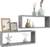 Two gray cube shelves are displayed against a white background. The top shelf holds decorative vases and diffusers. The bottom shelf displays a starfish sculpture and a small vase with decorative stems. There are also two framed pictures on the left side o Náhľad obrázku produktu