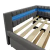 A close-up view of a grey upholstered bed frame with blue LED lighting along the headboard and wooden slats visible. Voir les images du produit