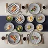 A top-down view of a table setting with multiple plates, bowls, and cups filled with food and drinks. Náhled obrázku produktu
