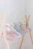 A row of pastel-colored children's hangers on a wooden rack. Anteprima dell’immagine prodotto