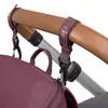 A close-up shot of a deep red backpack attached to a stroller handle using straps and clips. Produktbild-Vorschau