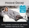 A woman wearing a grey hoodie blanket is lying on a white couch. Produktbild-Vorschau