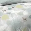 A close-up view of a duvet cover with a forest-themed print featuring deer and trees in various shades of green, yellow, and white on a light gray background. Produktbild-Vorschau