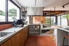 A modern kitchen with a wood-burning stove, concrete countertops, and wooden cabinets. Produktbild-Vorschau