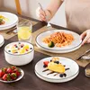 A table setting with plates of food and a person eating. Produktbild-Vorschau