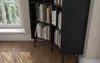 A close-up view of a black, curved bookshelf filled with books, placed on a wooden floor next to a window. Produktbild-Vorschau