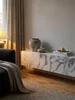 Geöffnete Klappe des hängenden TV-Schranks in Marmor-Optik, die den Stauraum mit Büchern und einer Schallplatte offenbart._#sku_SAFWL6.864# Produktbild-Vorschau