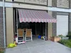 Awnings are installed on a balcony or patio, with outdoor furniture and plants visible. Produktbild-Vorschau