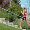 A woman runs up a set of outdoor stairs with a metal railing. Náhled obrázku produktu