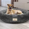 A dog is lying comfortably in a round, plush dog bed indoors. Produktbild-Vorschau