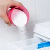 A hand is pouring white powder detergent from a pink cup into a washing machine dispenser. Produktbild-Vorschau