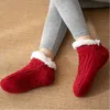 Rote Zopfmuster-Hausschuhe-Socken mit weißen flauschigen Bündchen und Anti-Rutsch-Noppen auf den Sohlen, getragen an den Füßen einer Person Náhľad obrázku produktu
