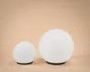 Two white spherical lamps of different sizes are placed on a light peach background. Produktbild-Vorschau