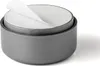 A gray, round furniture foot with a white protective layer being peeled back. Produktbild-Vorschau
