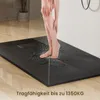 A person's legs are shown standing on a black shower tray under running water. Náhľad obrázku produktu