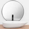 A white oval basin with a black faucet in front of a large round mirror. Podgląd zdjęcia produktu