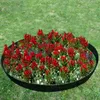 A circular garden bed with red flowers and green foliage, bordered by a black metal edge, set in a grassy lawn. Produktbild-Vorschau