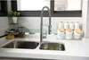 A kitchen sink with a faucet and various containers on the countertop. Náhled obrázku produktu