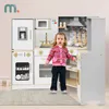 A young child stands in front of a toy kitchen set. Produktbild-Vorschau