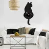 A living room with a sofa, coffee table, and a cat-shaped wall clock. Produktbild-Vorschau