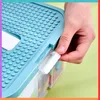 A hand is shown interacting with a blue plastic storage container with clear drawers. Produktbild-Vorschau