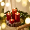 Four red LED candles of varying heights are arranged on a wooden base, surrounded by pine branches and fairy lights. Produktbild-Vorschau