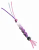 A close-up of a handmade craft item, possibly a keychain or charm, made of braided cords and beads. Anteprima dell’immagine prodotto
