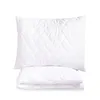 A white quilted pillow and a folded white quilted blanket are stacked on a white background. Náhled obrázku produktu