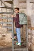 A young boy with a backpack climbs a spiral staircase. Produktbild-Vorschau