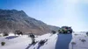 Several off-road vehicles driving through a snowy, mountainous landscape. Produktbild-Vorschau