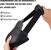 A hand holding a black shoe cover with elastic straps. Produktbild-Vorschau