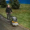 A person is using a weed brush machine on a paved path next to a grassy slope. Produktbild-Vorschau