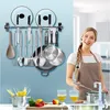 A woman in an apron is in a kitchen, with cooking utensils and pots displayed on a wall rack. Produktbild-Vorschau