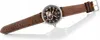 A watch with a brown leather strap and a dark brown dial, shown from a diagonal angle against a white background. Náhled obrázku produktu