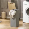A laundry room scene with a washing machine, laundry hamper, and trash can. Produktbild-Vorschau