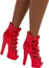 A close-up view of a pair of red high-heeled shoes on a doll's legs. Podgląd zdjęcia produktu
