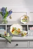 Easter-themed tableware and decorations displayed on a shelf. Produktbild-Vorschau