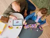 A father and daughter are building a LEGO train on a table, using a tablet for instructions. Produktbild-Vorschau