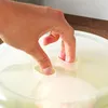 A hand is shown pressing down on a transparent lid with two fingers inserted into small openings. Anteprima dell’immagine prodotto