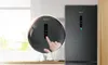 A close-up of a refrigerator's digital display and a hand interacting with it, with the refrigerator in the background. Produktbild-Vorschau