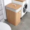 A bamboo laundry basket is placed next to a washing machine in a laundry room. Náhled obrázku produktu