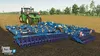 A green tractor is pulling a blue farming implement through a field. Podgląd zdjęcia produktu