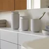 A bathroom counter with soap dispensers, a toothbrush holder, and a toothbrush. Produktbild-Vorschau